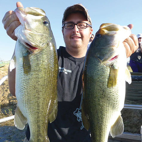 image of a fisherman holding two bass