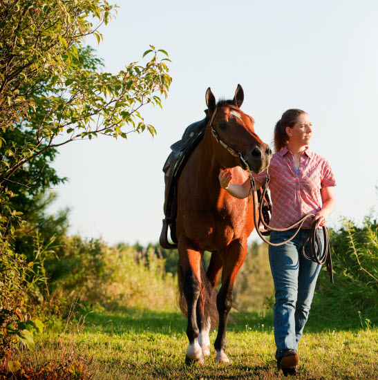 image of a woman walking a horse