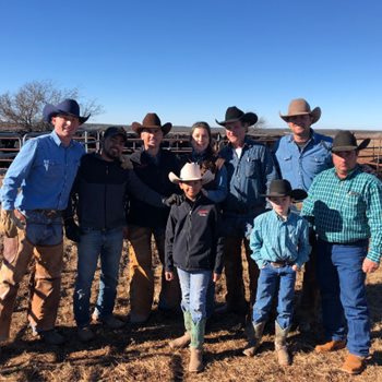 Nine Vest Ranch team members standing in front of a cattle pen